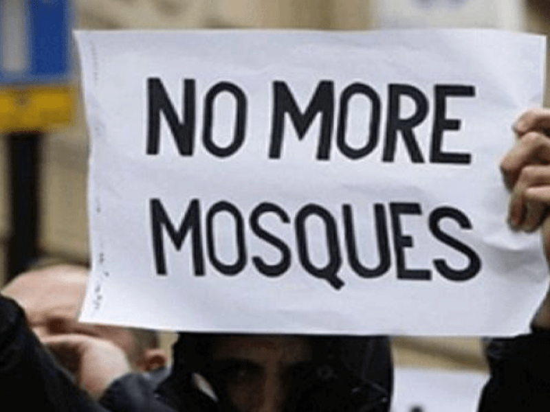 someone holding a placard which says "no more mosques"