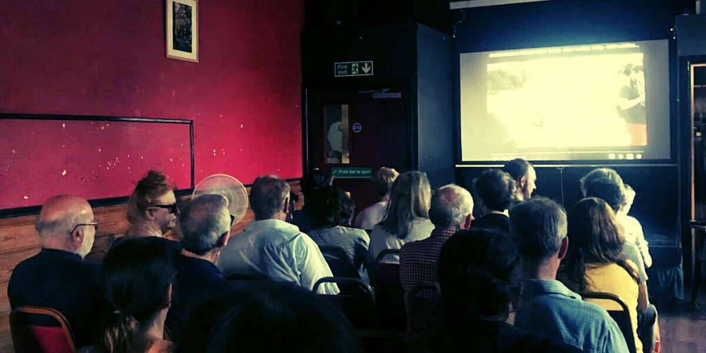 Several people are at a film screening, watching a film