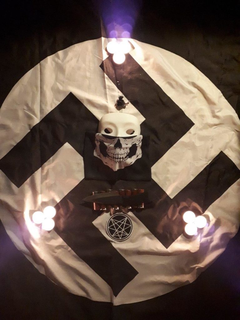 a white swastika with a menacing-looking skull in the middle 