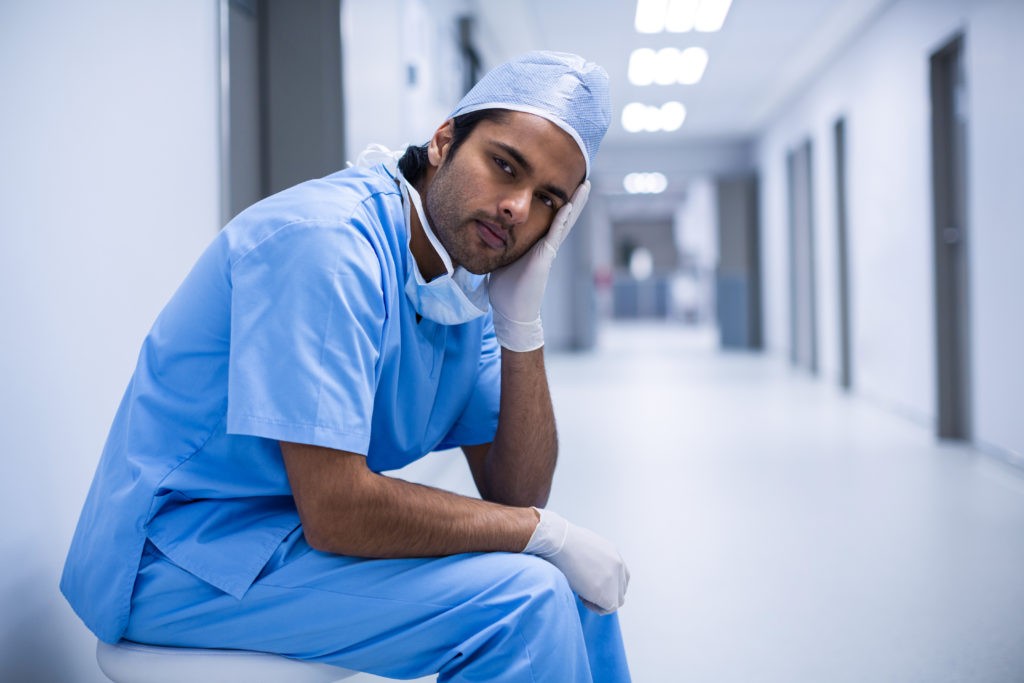A picture of a surgeon sitting down, looking sad and stressed out