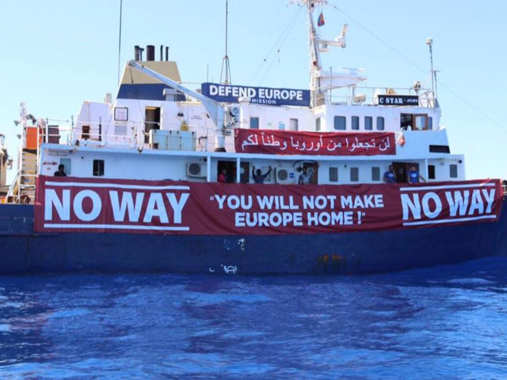 A ferry with banners draped on the side. Writing on the drapes says "Defend Europe...No way...You will not make Europe home!".