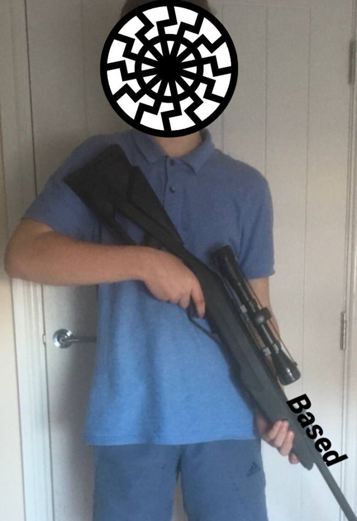 A teenager, with his face covered, is holding a rifle.