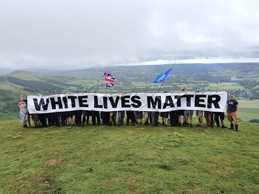Several people holding a banner that says "White lives matter"